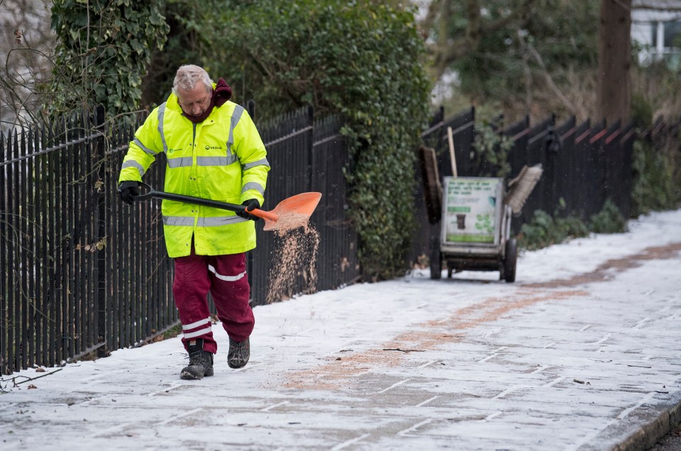 A council worker spreads grit on the pavement at Primrose Hill in Camden, North London