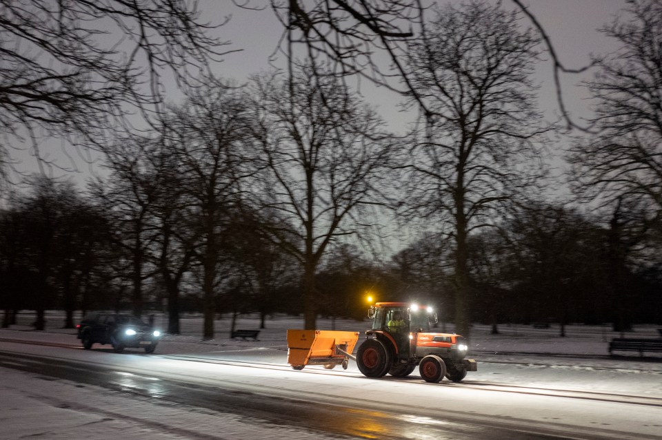 A worker drives a gritter in London's Greenwich Park during a snow shower