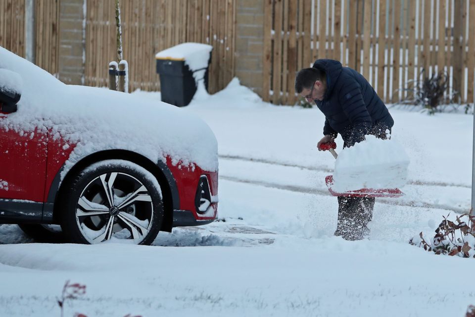 A man clears snow from his drive in Larbert, near Falkirk