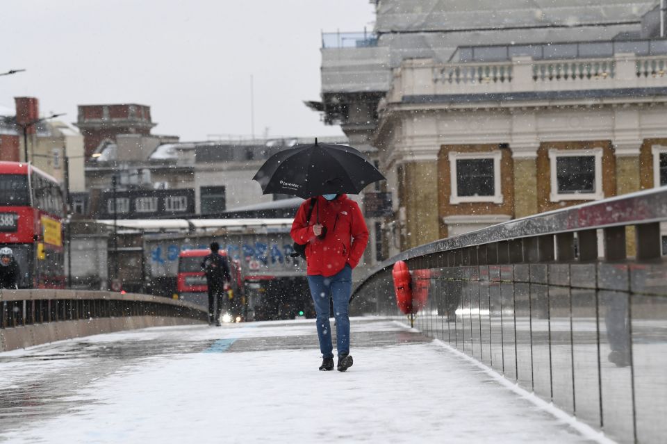 Commuters cross London Bridge in the falling snow as bitterly cold winds continue to grip much of the nation