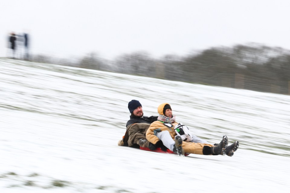 People sledge down Parliament Hill in Hampstead Heath, London