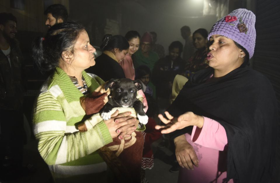 Residents - one holding a puppy - speak on a street in Amritsar, Northern India following the quake