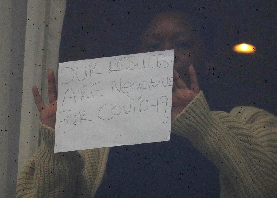 A traveller holds up a sign reading: 'Our results are negative for Covid-19'