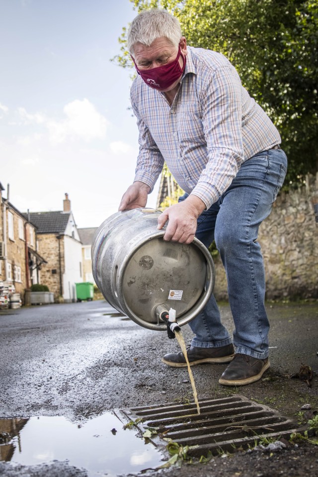 Patrick Mahoney, landlord of The Winchester Arms, pours out-of-date beer down the drain in Taunton, February 18 2021