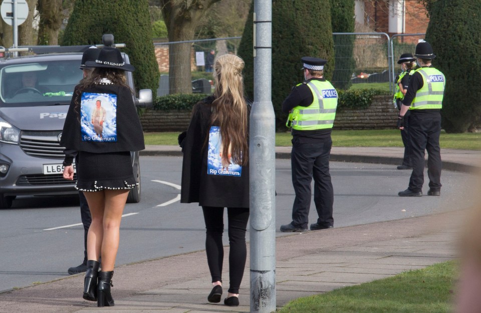 Mourners making their way to the funeral wearing jackets with a picture of the deceased woman