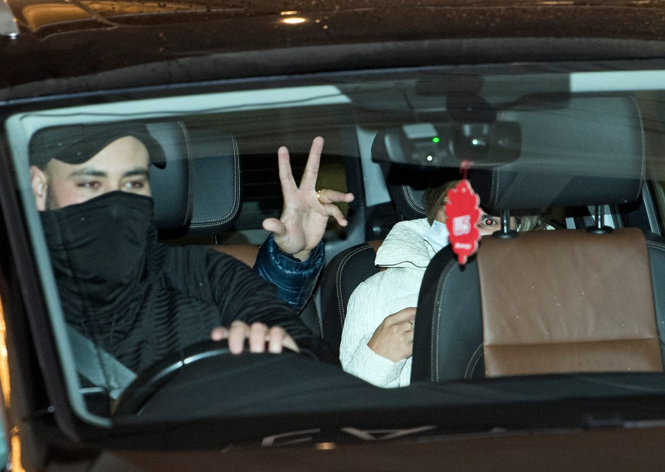 Joyful travellers salute photographers as they leave their quarantine hotel in Heathrow