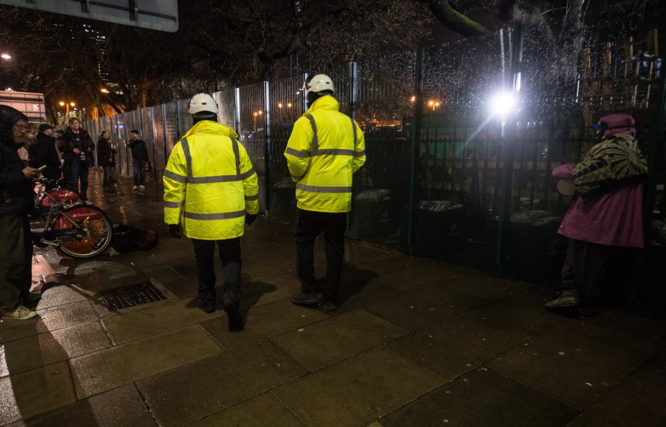 Security guards walk past protestors last night