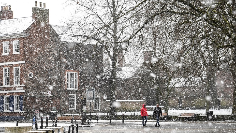 People walk through a snow shower in York