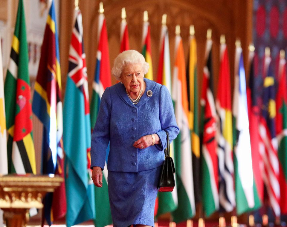 Queen Elizabeth II walks past Commonwealth flags in St George's Hall at Windsor Castle to mark Commonwealth Day