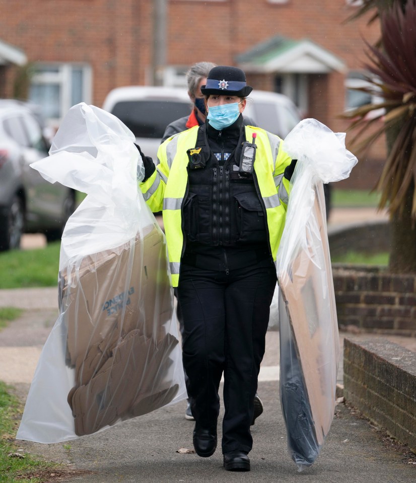 A police officer carries evidence in plastic bags