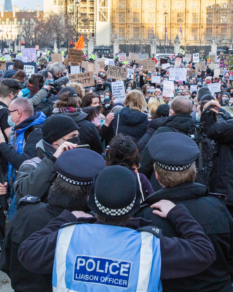 Police watch on as a large group of protesters gather in front of Parliament