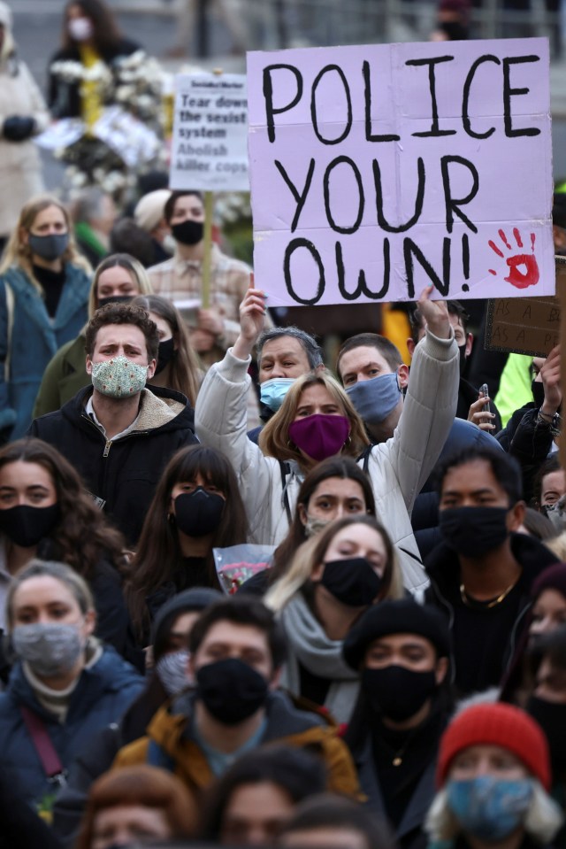 Women hold signs during a protest at Parliament Square