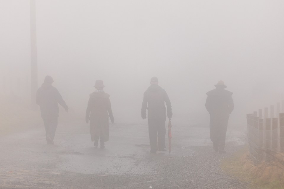 Locals walk through heavy fog in Horwich, Greater Manchester