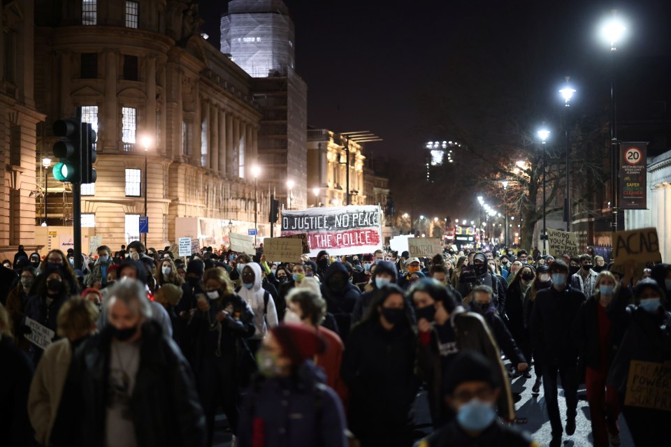 Demonstrators holding placards walk along Whitehall