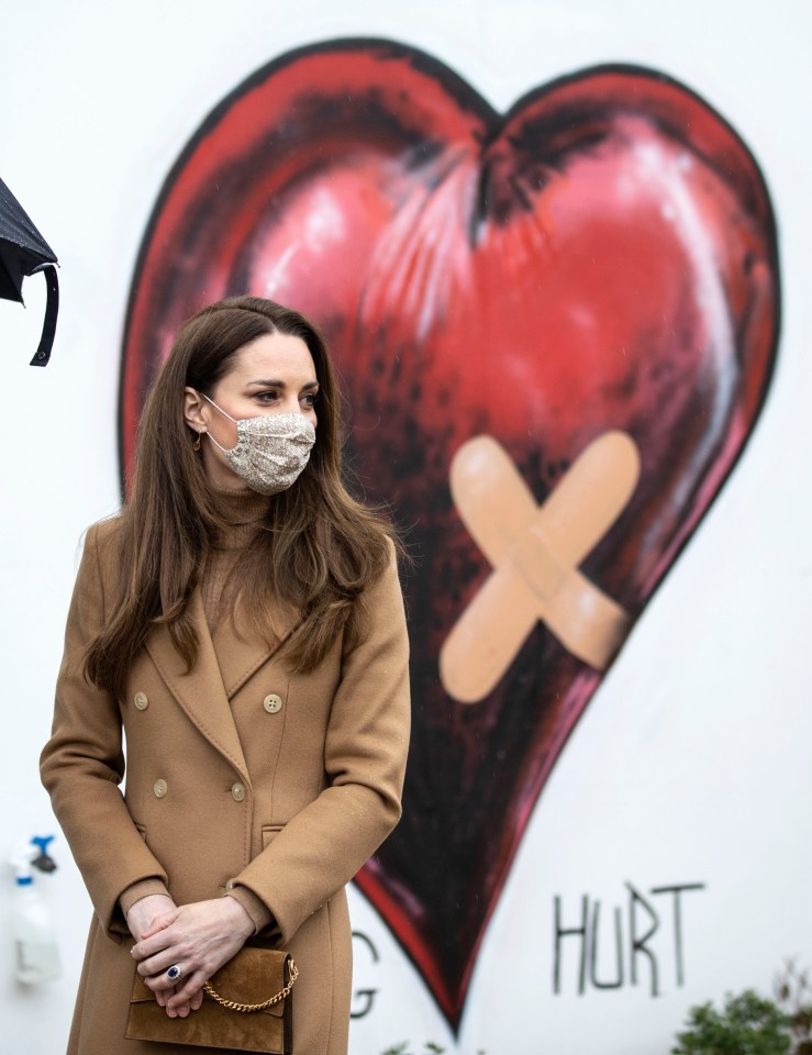 Kate stands in front of a heart mural