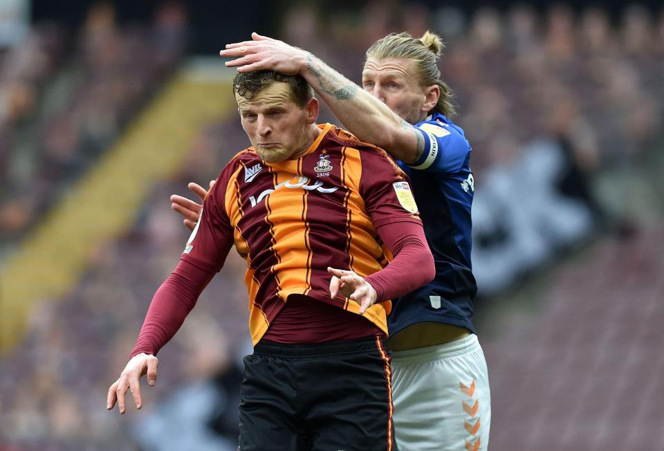 Oldham Athletic's Carl Piergianni tussles with Bradford striker Danny Rowe