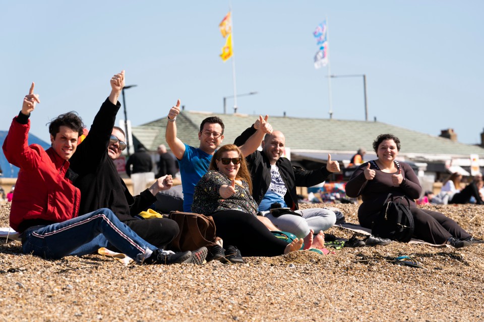 A group of pals give a thumbs up as they enjoy the sunshine on the beach in Southend