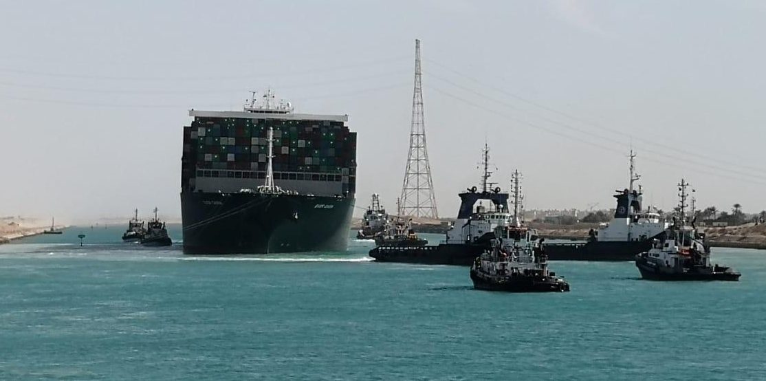 A fleet of tugboats help guide the giant vessel through the narrow canal waters