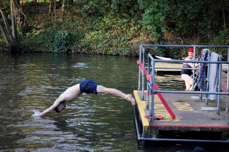 A swimmer enters the water at the Hampstead Heath ponds to cool off in London