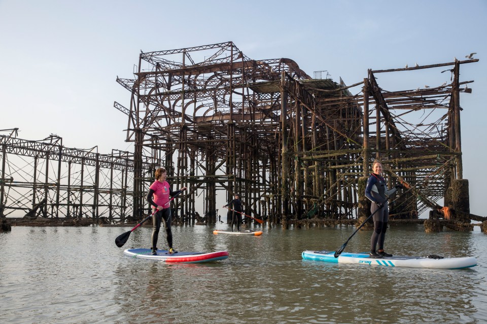 Paddle boarders near the old West Pier in Brighton just after sunrise