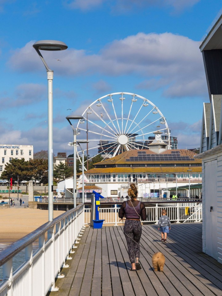 A woman walks her dog on a warm spring day at Bournemouth