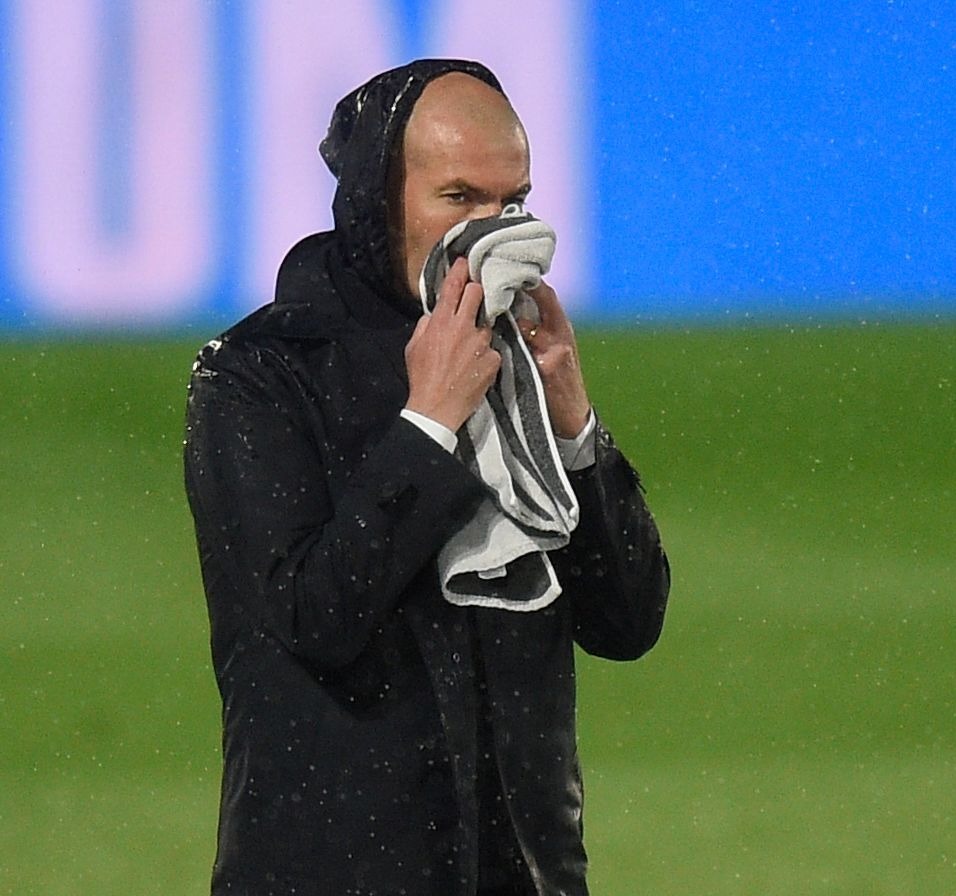 Real Madrid boss Zinedine Zidane wipes some rain off his face