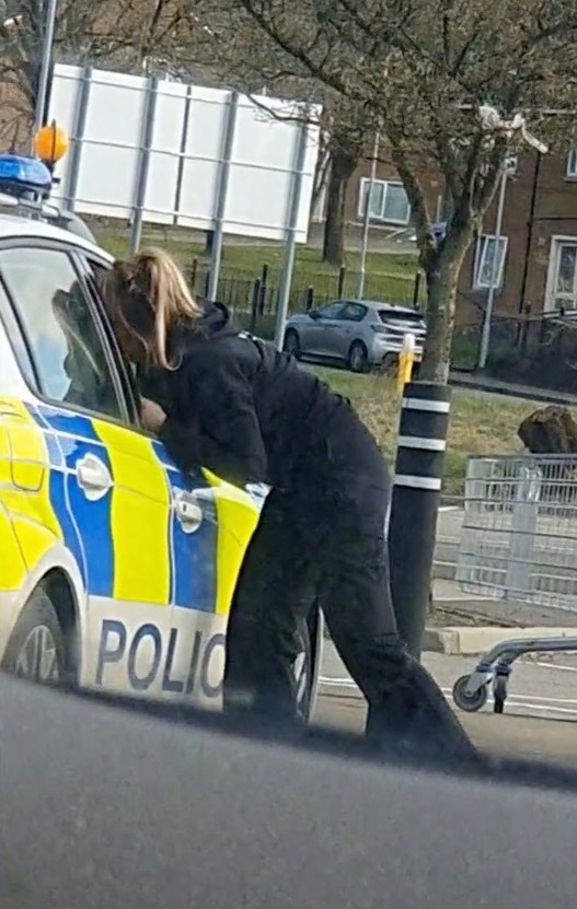 The female officer got out of the car and went to the driver's side, where they continued kissing