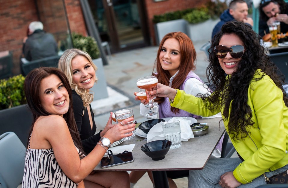 A group of friends pose for a photograph in the beer garden at Dukes 92 bar in Manchester