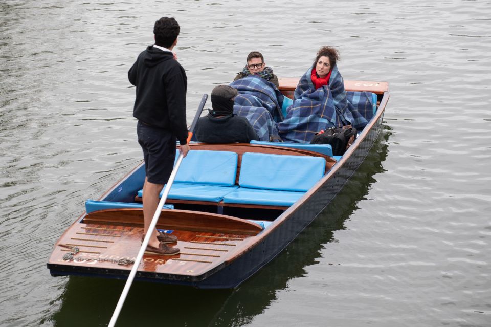 People wrap in blankets as they take a punt tour along the River Cam in Cambridge