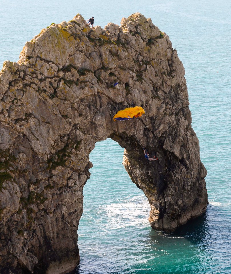 Base jumpers leaping into the sea from the arch