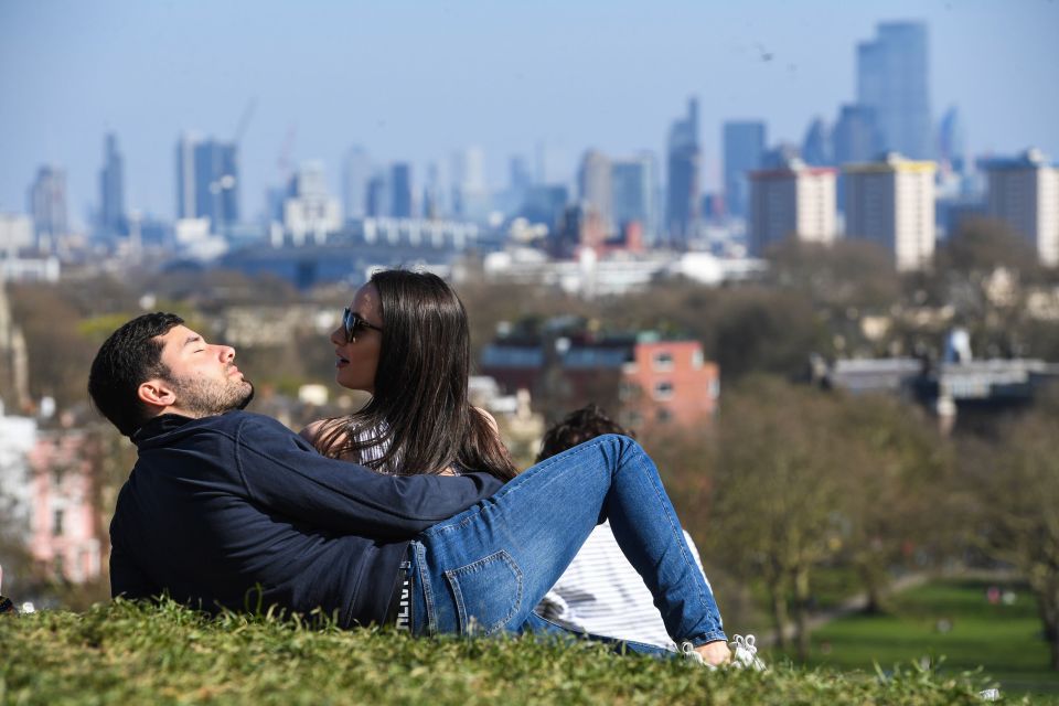 A couple basking in the sunshine in London's Primrose Hill park