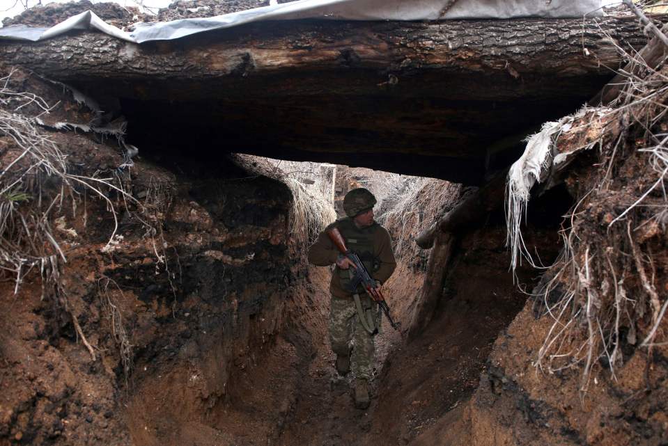 A Ukrainian serviceman patrols a trench along a position at the frontline