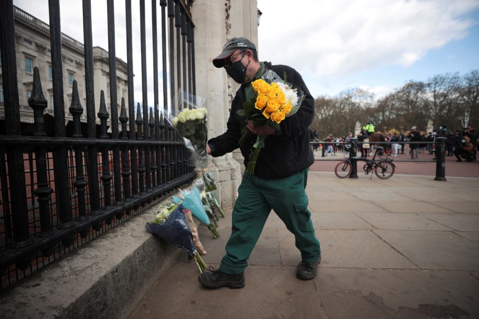 A mourner wearing a face mask arrives at the Palace with two bouquets of flowers