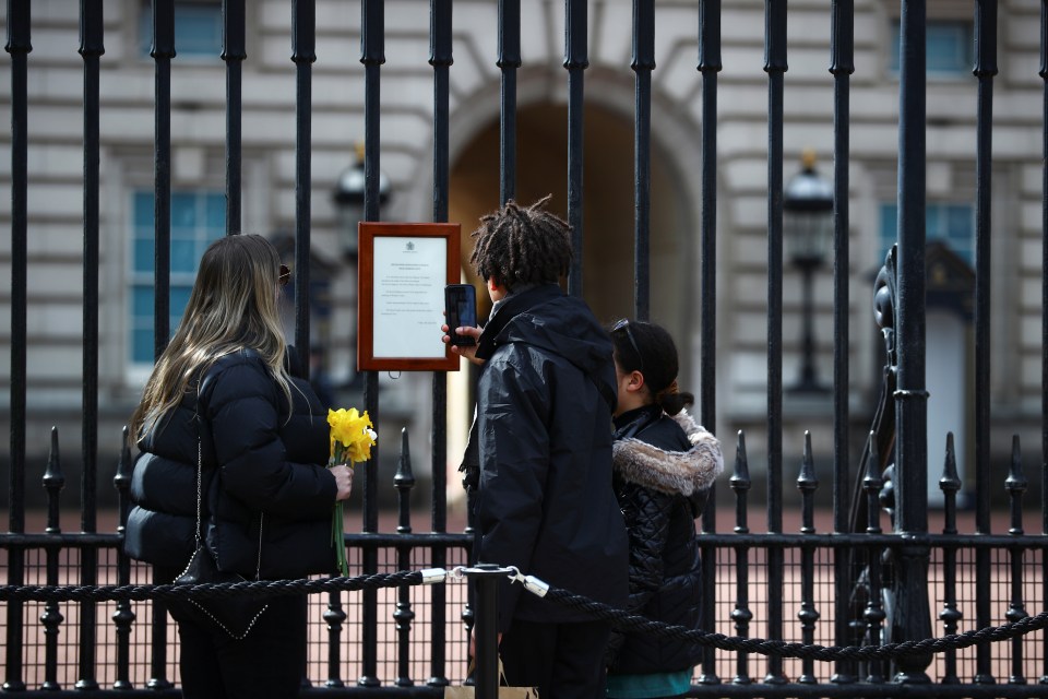 Mourners take a moment to read the plaque announcing Prince Philip's death