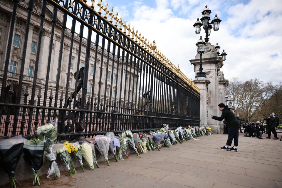 Bouquets of flowers have been lined up against the railings of Buckingham Palace