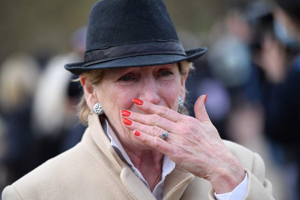 A woman reacts after laying a floral tribute at the gates of Buckingham Palace