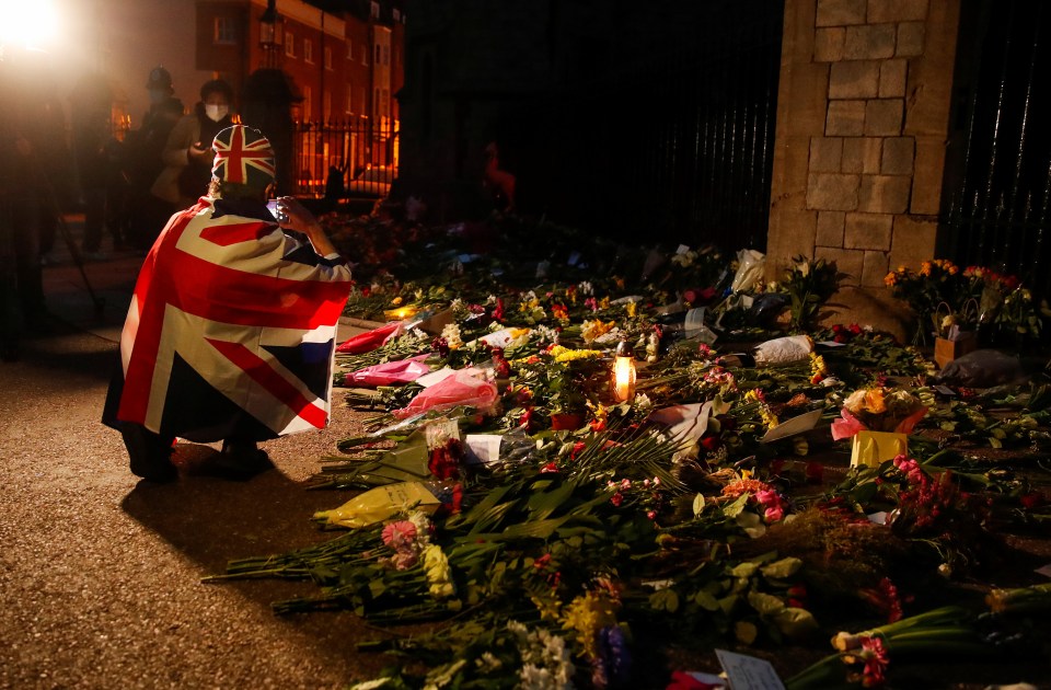 A mourner draped in a flag last night took photos of the flowers