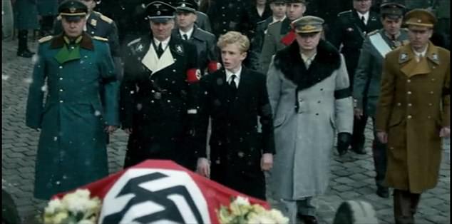 a group of men in military uniforms are standing around a coffin .