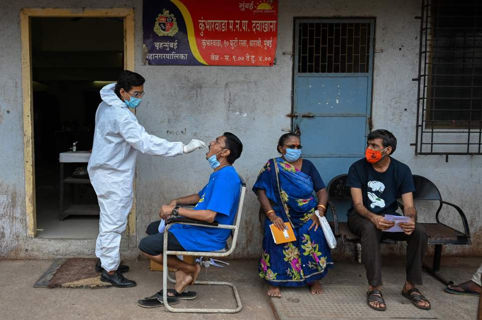 A health worker takes a swab sample of a resident for a Covid-19 coronavirus test at a medical centre in Dharavi in Mumbai