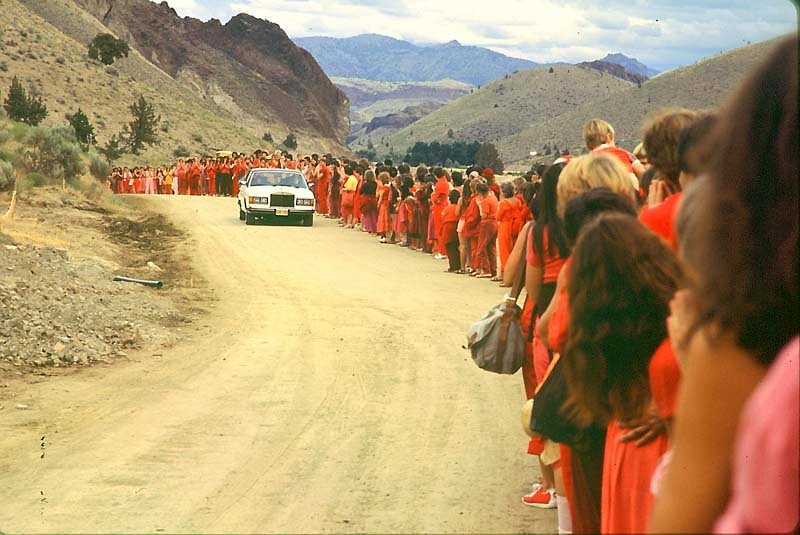 Red-robed devotees line up to watch their leader drive past