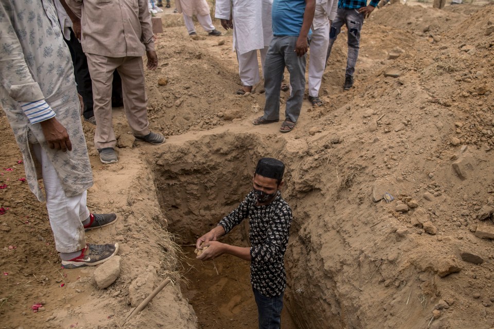 Family members and relatives prepare to bury a body of a Covid patient