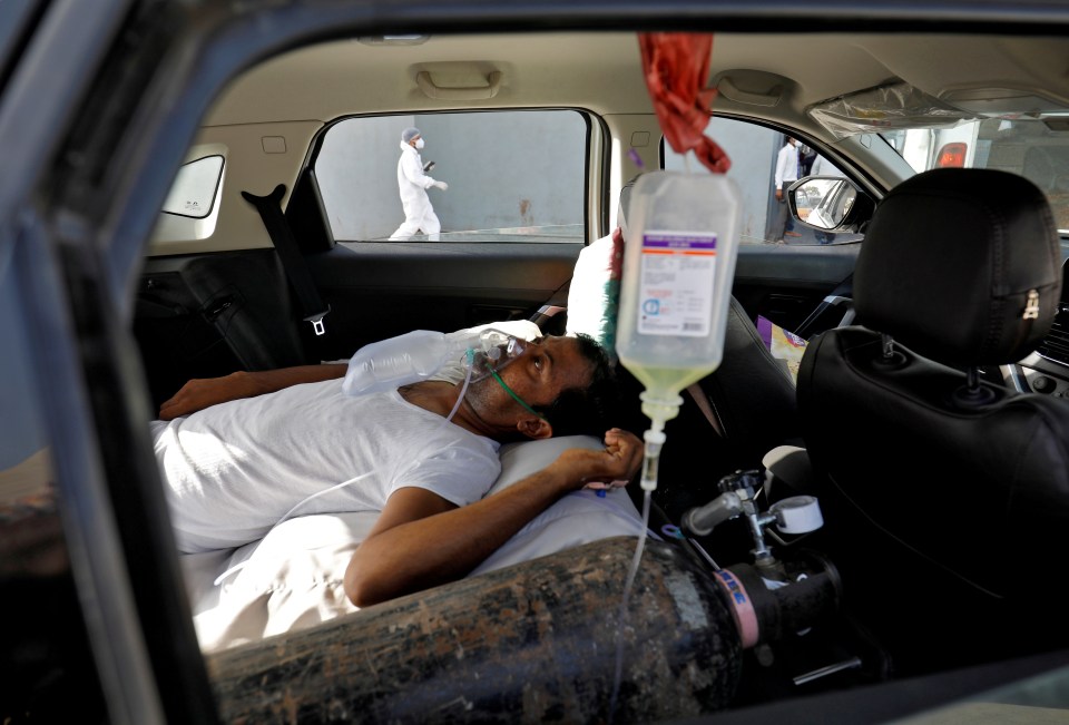 A patient with breathing problems lies inside a car while waiting to enter a Covid hospital for treatment in Ahmedabad, India