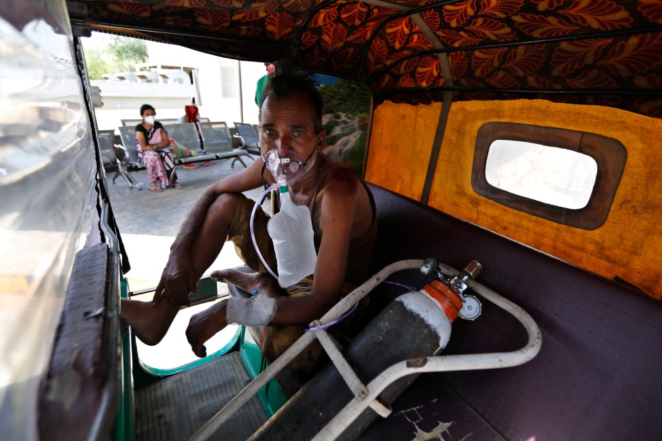 A Covid patient wearing oxygen mask waits inside an auto rickshaw to be attended in Ahmedabad, India