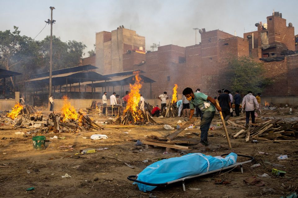 A man prepares a funeral pyre to cremate a Covid patient's body in New Delhi, India