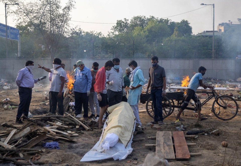 Relatives prepare to cremate the body of a person who died due to coronavirus at a crematorium ground in New Delhi, India