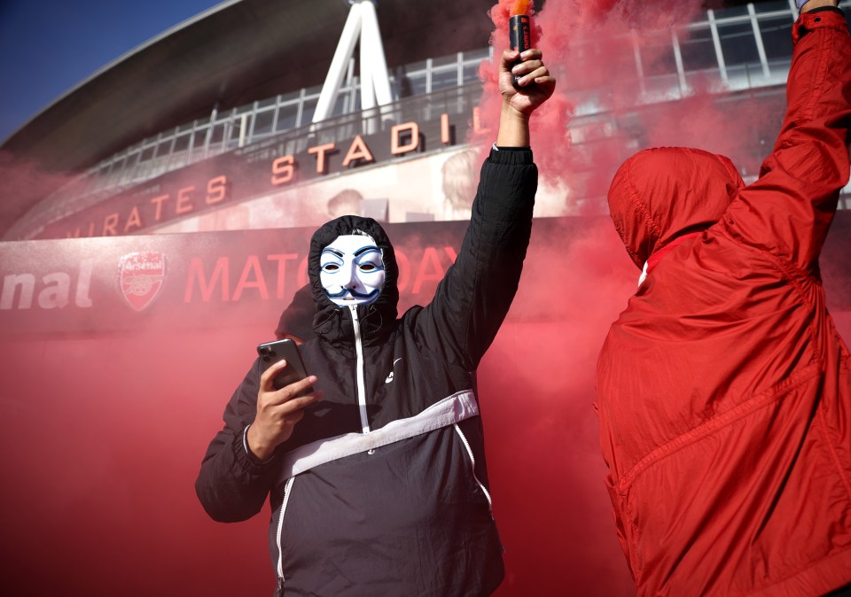 An Arsenal supporters lets off a red flare outside the stadium before the clash with Everton