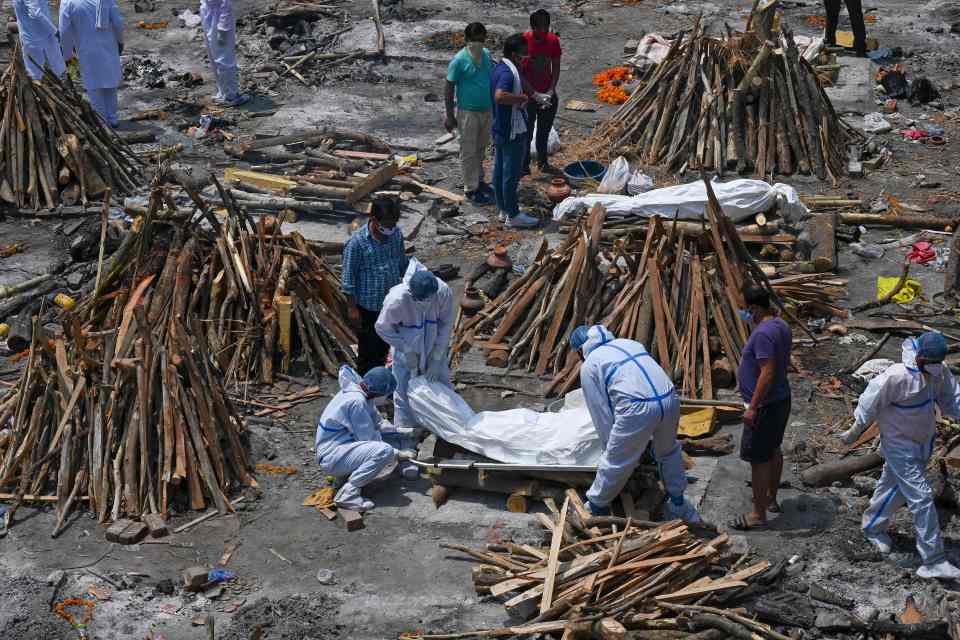 Workers in hazmat suits prepare pyres at another cremation ground in Delhi today