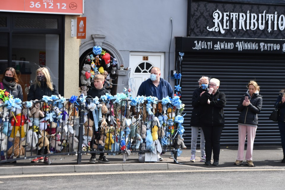 Locals and family members today lined the High Street with banners, flowers and soft toys in tribute to the tragic tot