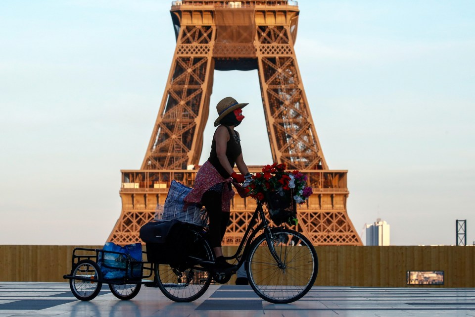 A woman, wearing a mask, rides her bicycle near the Eiffel tower at Trocadero square in Paris earlier this month