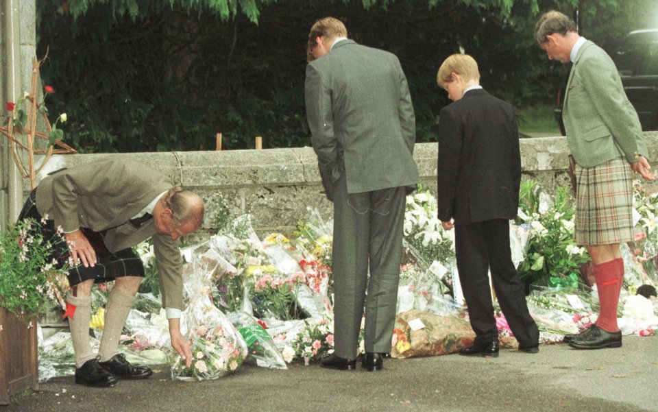 William and brother Harry look at flowers left in tribute to their mother following her death in 1997